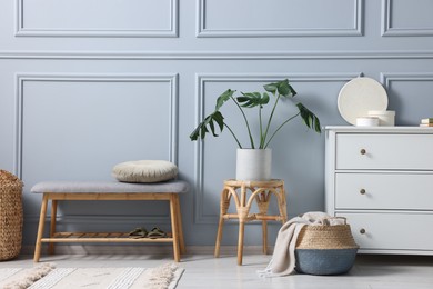 Photo of Stylish interior with stool and chest of drawers near light grey wall