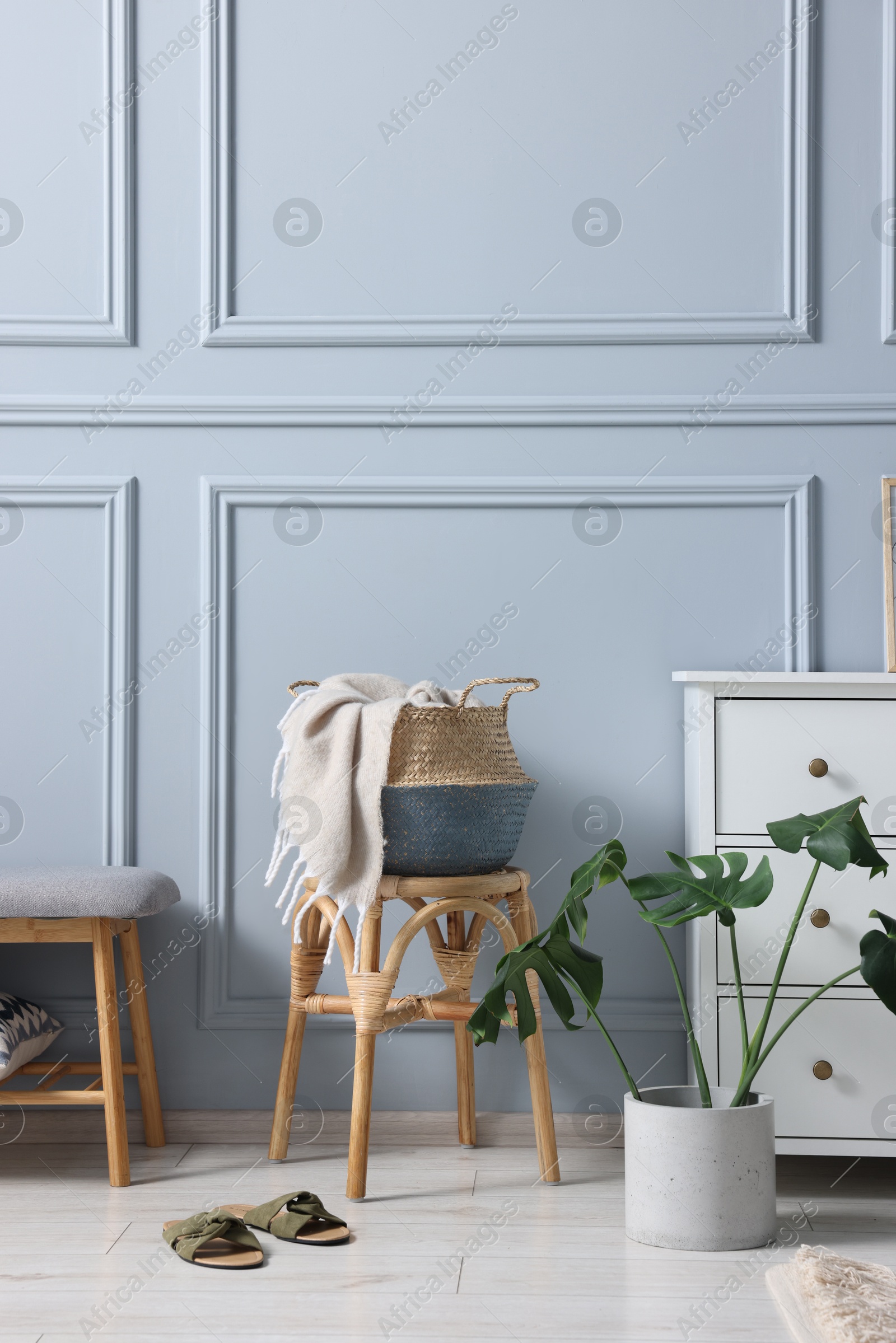 Photo of Stylish interior with stool and chest of drawers near light grey wall