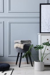 Photo of Stylish interior with stool and chest of drawers near light grey wall