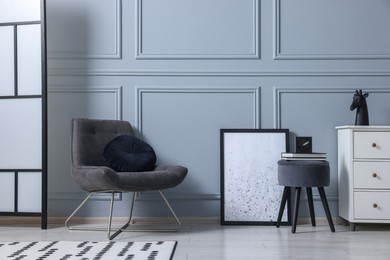 Photo of Stylish interior with stool and chest of drawers near light grey wall