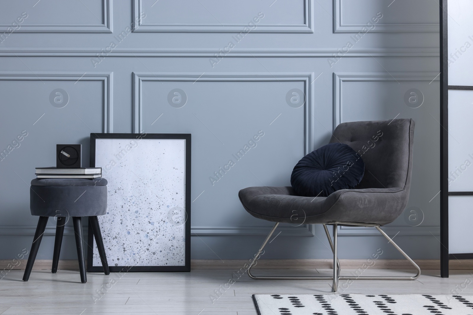 Photo of Stylish stool, chair and books near light grey wall indoors