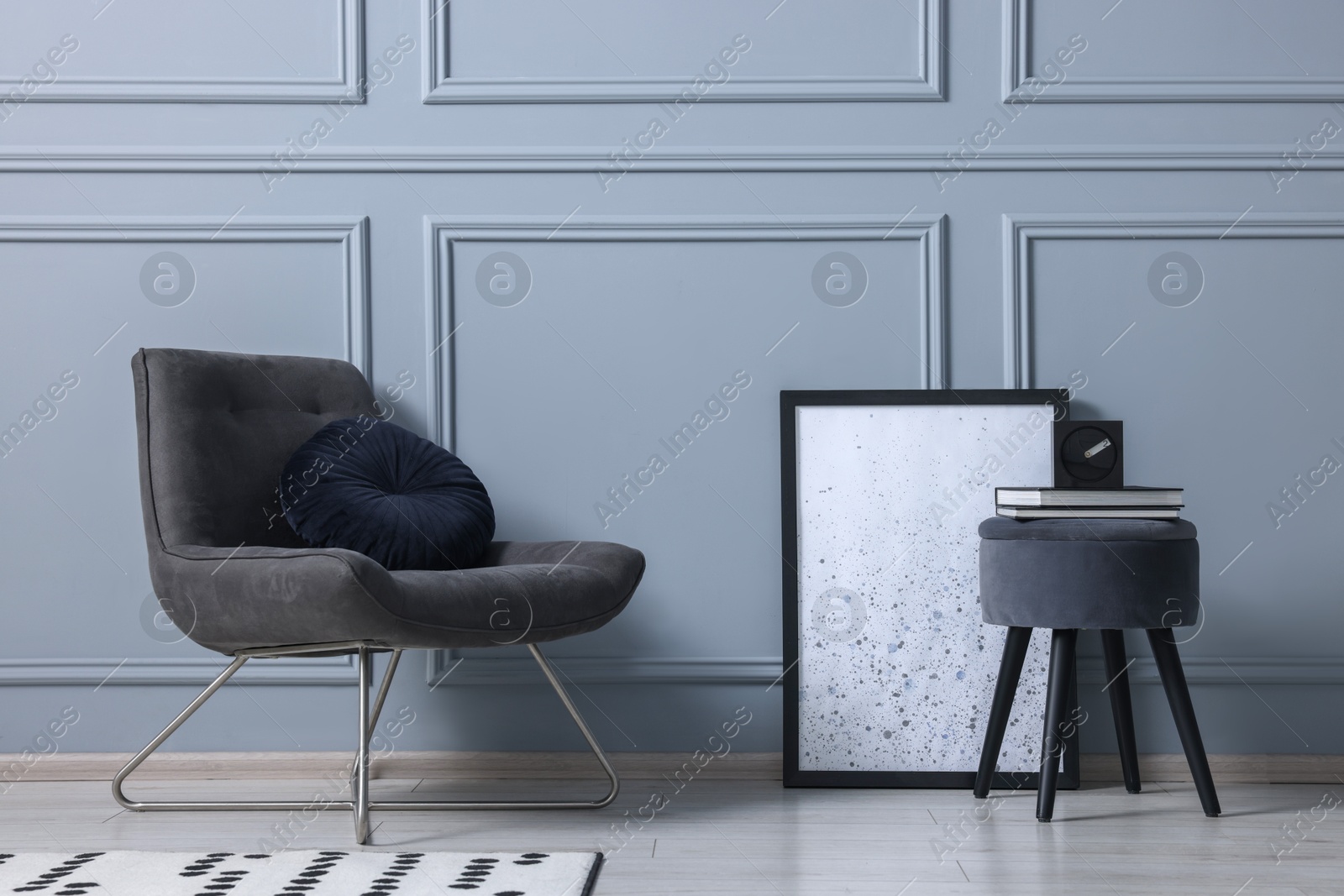 Photo of Stylish stool, chair and books near light grey wall indoors