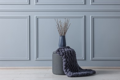 Photo of Stylish stool and vase near light grey wall indoors