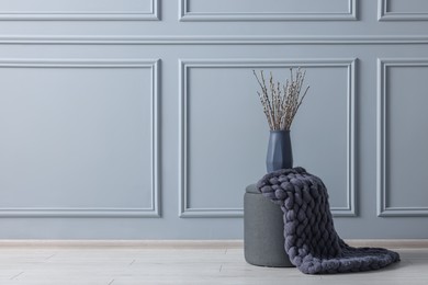 Photo of Stylish stool and vase near light grey wall indoors, space for text