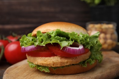 Delicious vegetarian burger with chickpea cutlet on wooden board, closeup