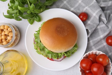 Photo of Delicious vegetarian burger with chickpea cutlet and ingredients on white table, flat lay