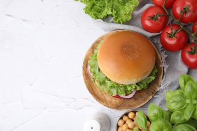 Delicious vegetarian burger with chickpea cutlet and ingredients on white textured table, flat lay. Space for text