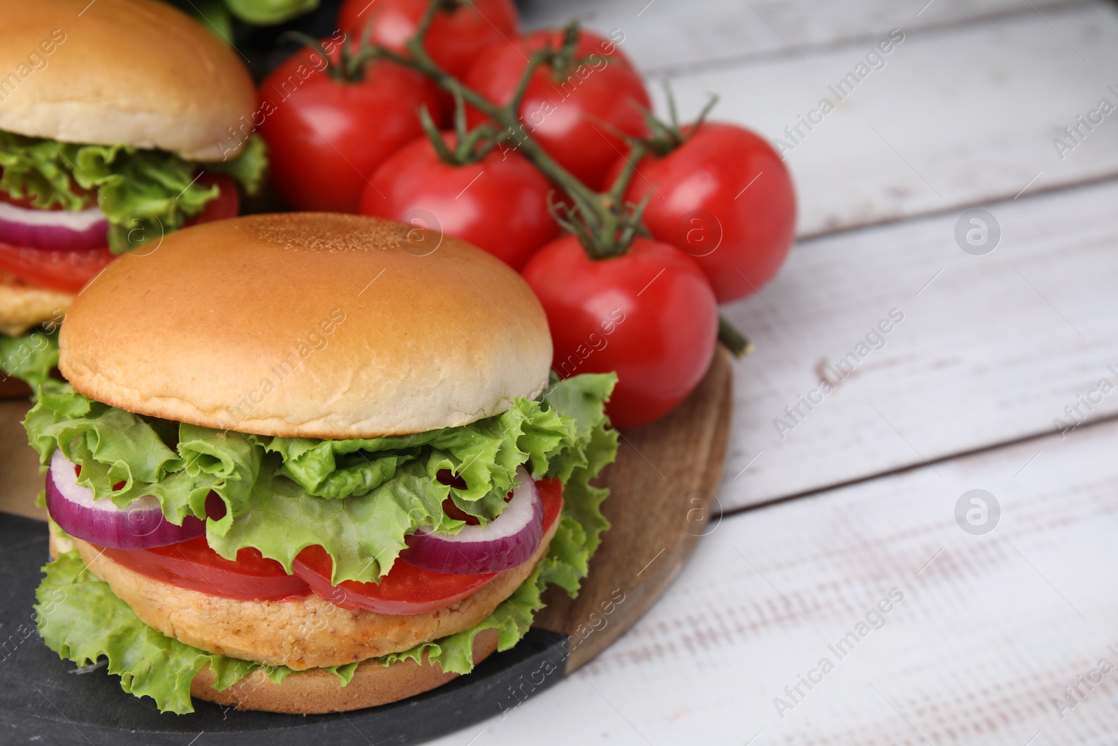 Photo of Delicious vegetarian burgers with chickpea cutlets and tomatoes on white wooden table. Space for text