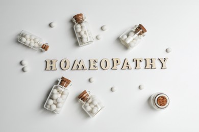 Photo of Word Homeopathy and pills on white background, flat lay