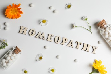 Photo of Word Homeopathy, pills and medicinal herbs on white background, flat lay