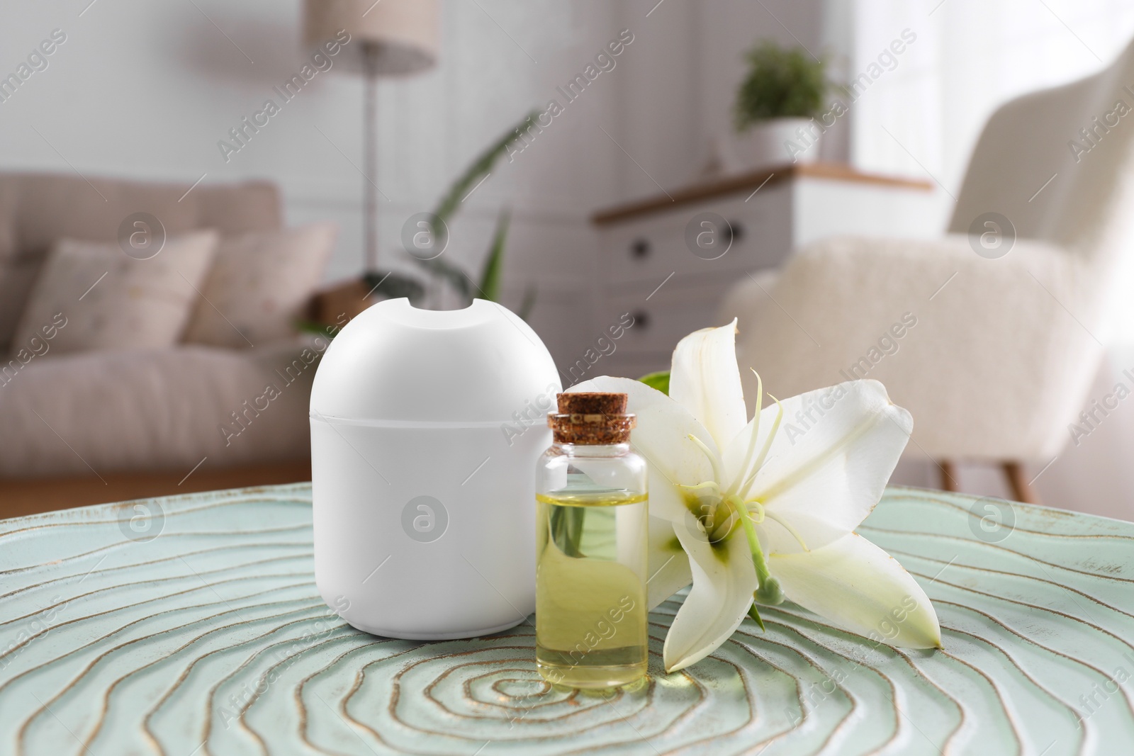 Photo of Essential oil diffuser, cosmetic product and lily flower on table at home