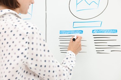 Developing UI design. Woman drawing website wireframe on whiteboard indoors, closeup