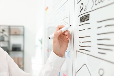 Developing UI design. Woman drawing website wireframe on whiteboard indoors, closeup