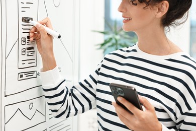 Developing UI design. Woman drawing website wireframe on whiteboard indoors, closeup