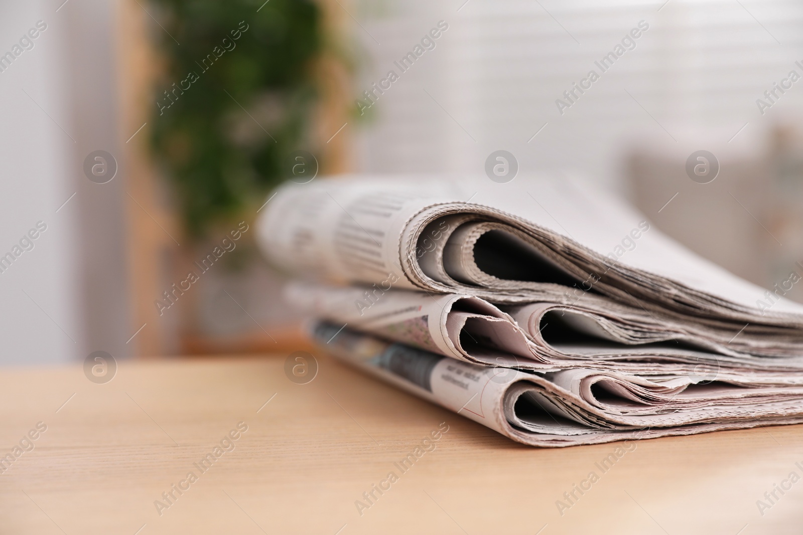 Photo of Stack of newspapers in different languages on table indoors, closeup