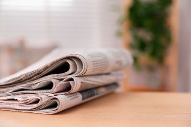 Stack of newspapers in different languages on table indoors