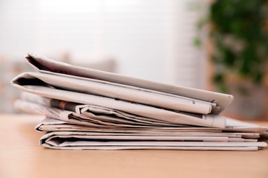 Photo of Stack of newspapers in different languages on table indoors, closeup