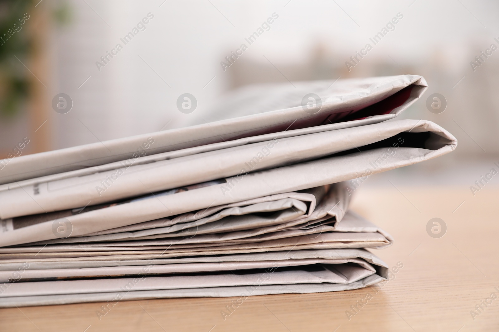 Photo of Stack of newspapers in different languages on table indoors, closeup