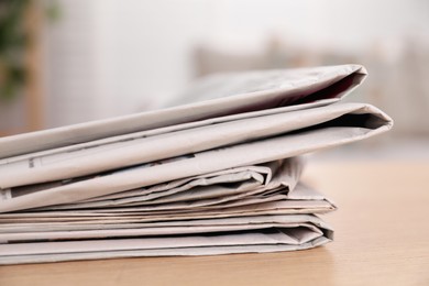 Photo of Stack of newspapers in different languages on table indoors, closeup