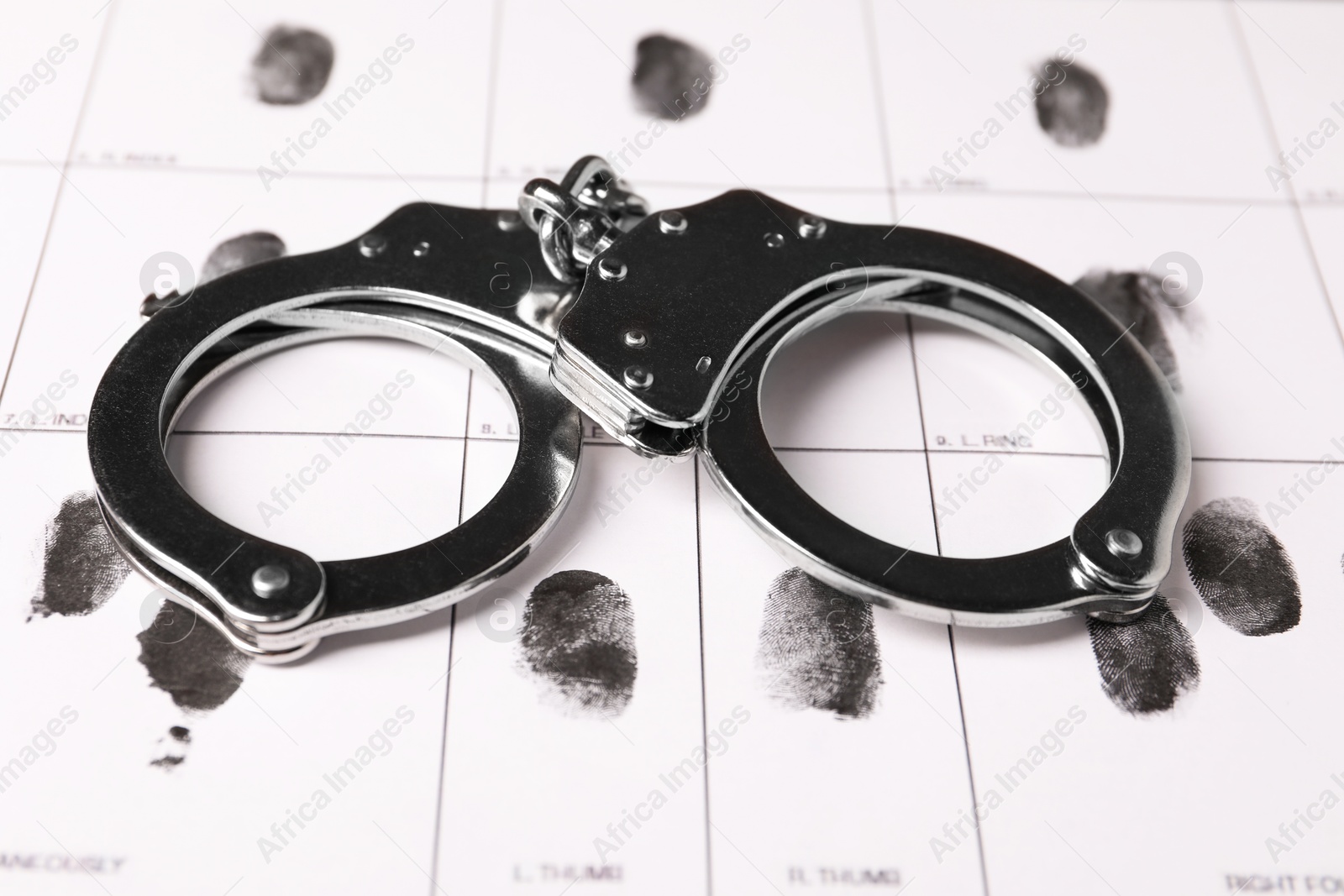 Photo of Human fingerprints and handcuffs on paper, closeup. Criminal conviction