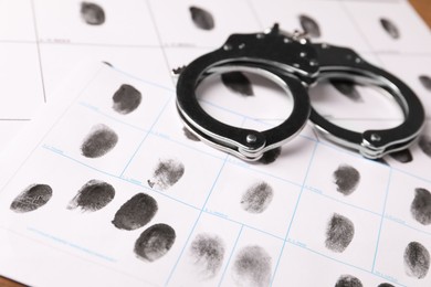 Photo of Human fingerprints and handcuffs on paper, closeup. Criminal conviction