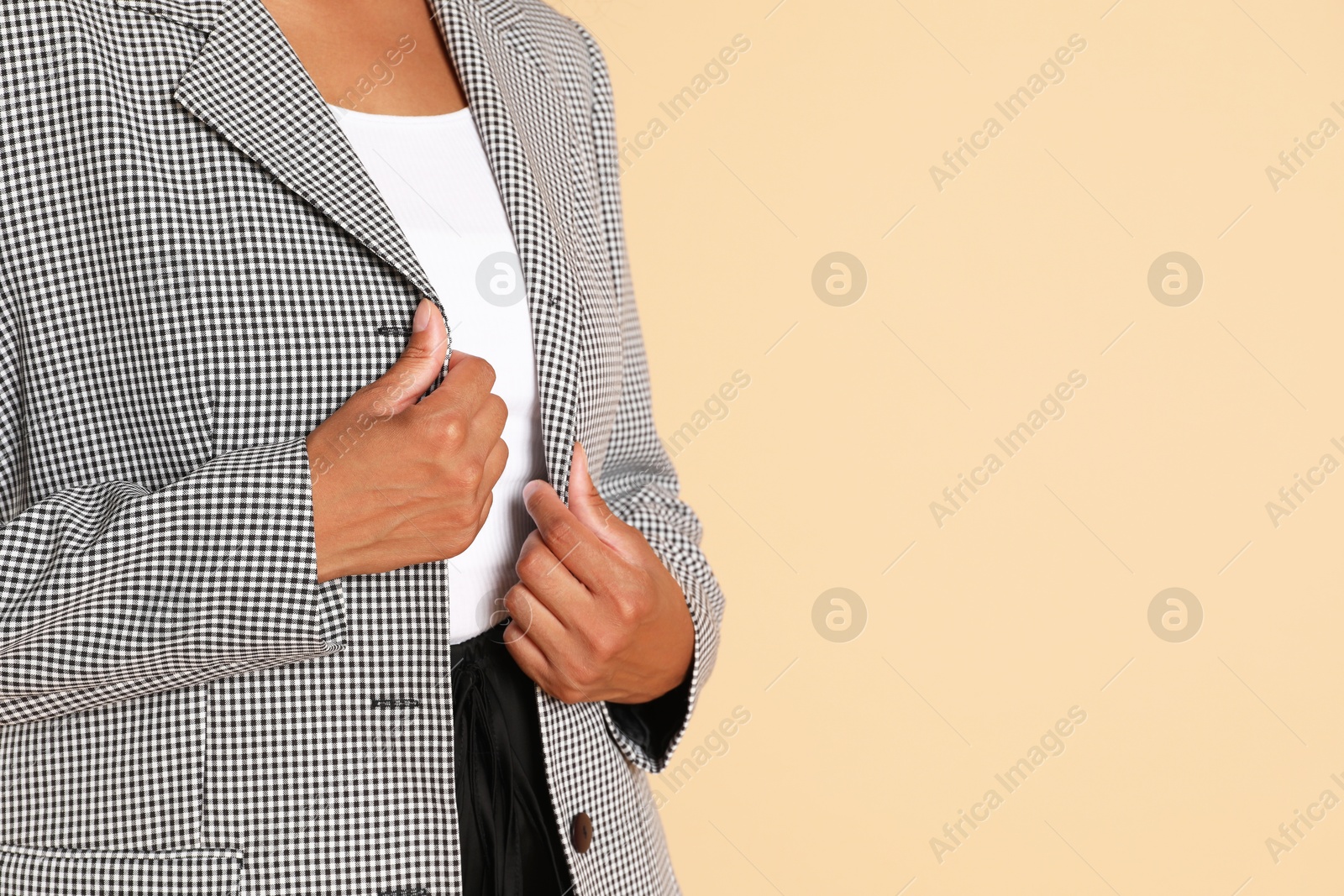 Photo of Woman in stylish jacket on beige background, closeup. Space for text