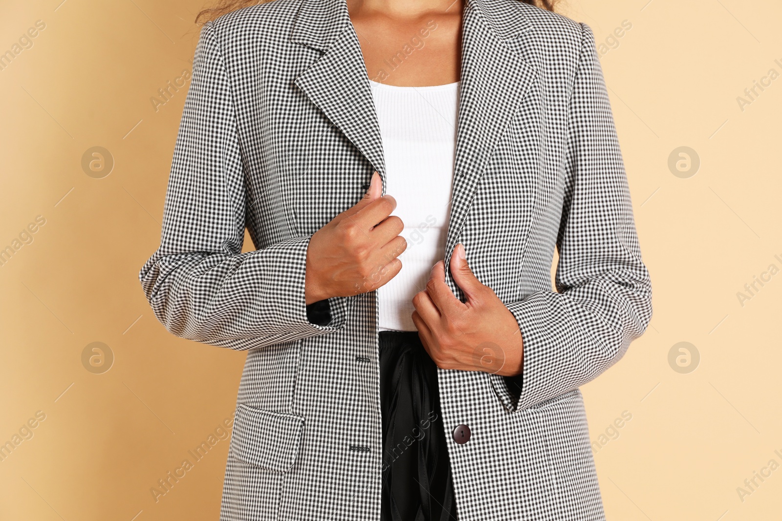 Photo of Woman in stylish jacket on beige background, closeup