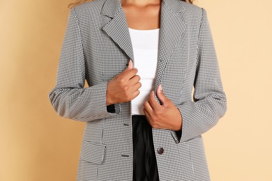 Woman in stylish jacket on beige background, closeup