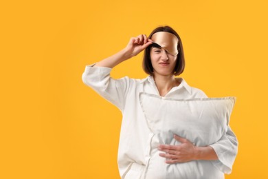 Overslept young woman with sleep mask and pillow on yellow background. Space for text