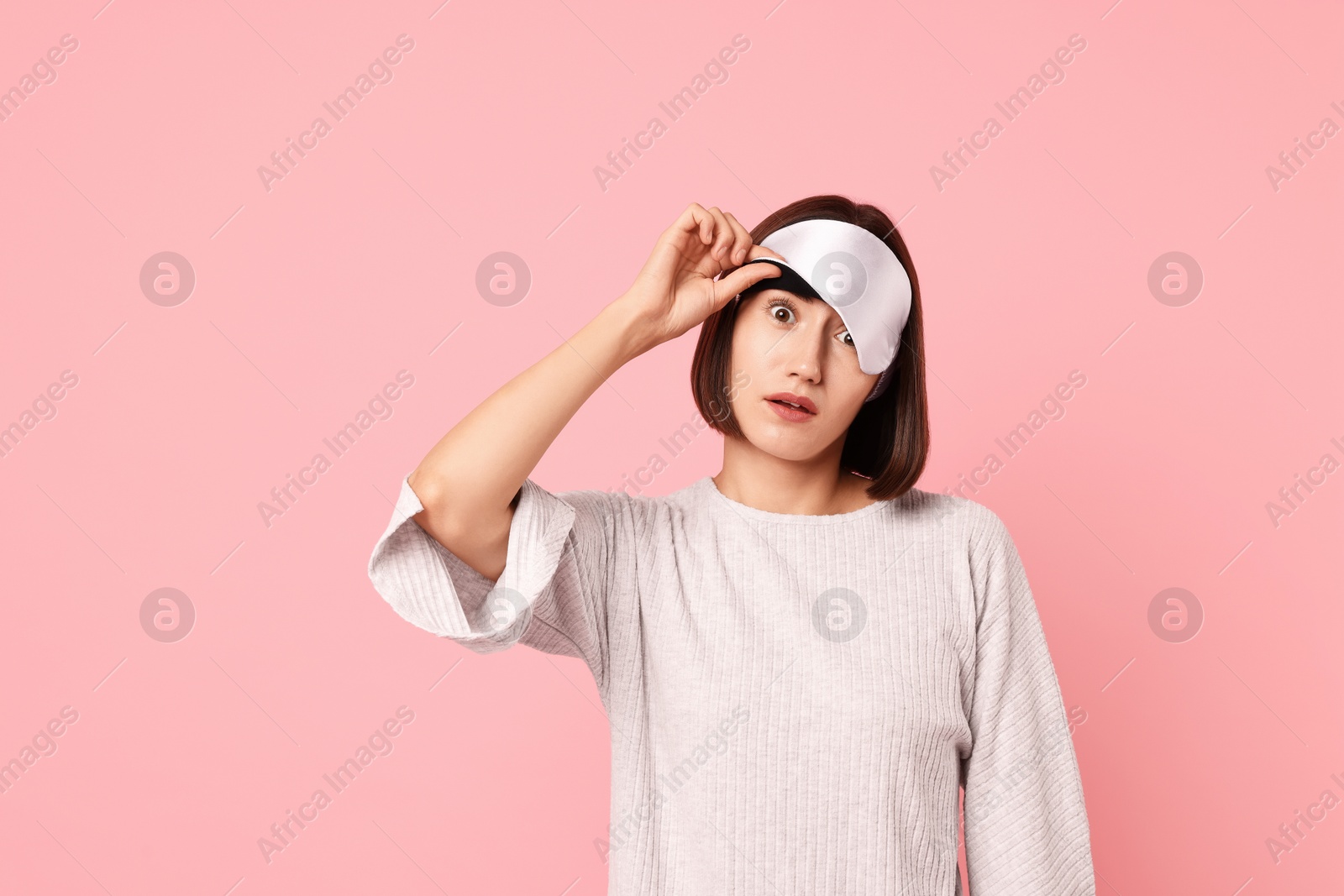 Photo of Overslept young woman with sleep mask on pink background