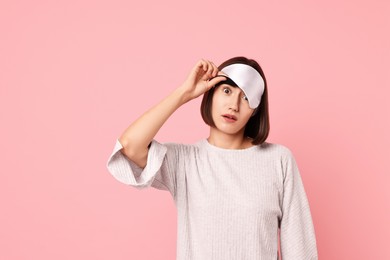 Photo of Overslept young woman with sleep mask on pink background