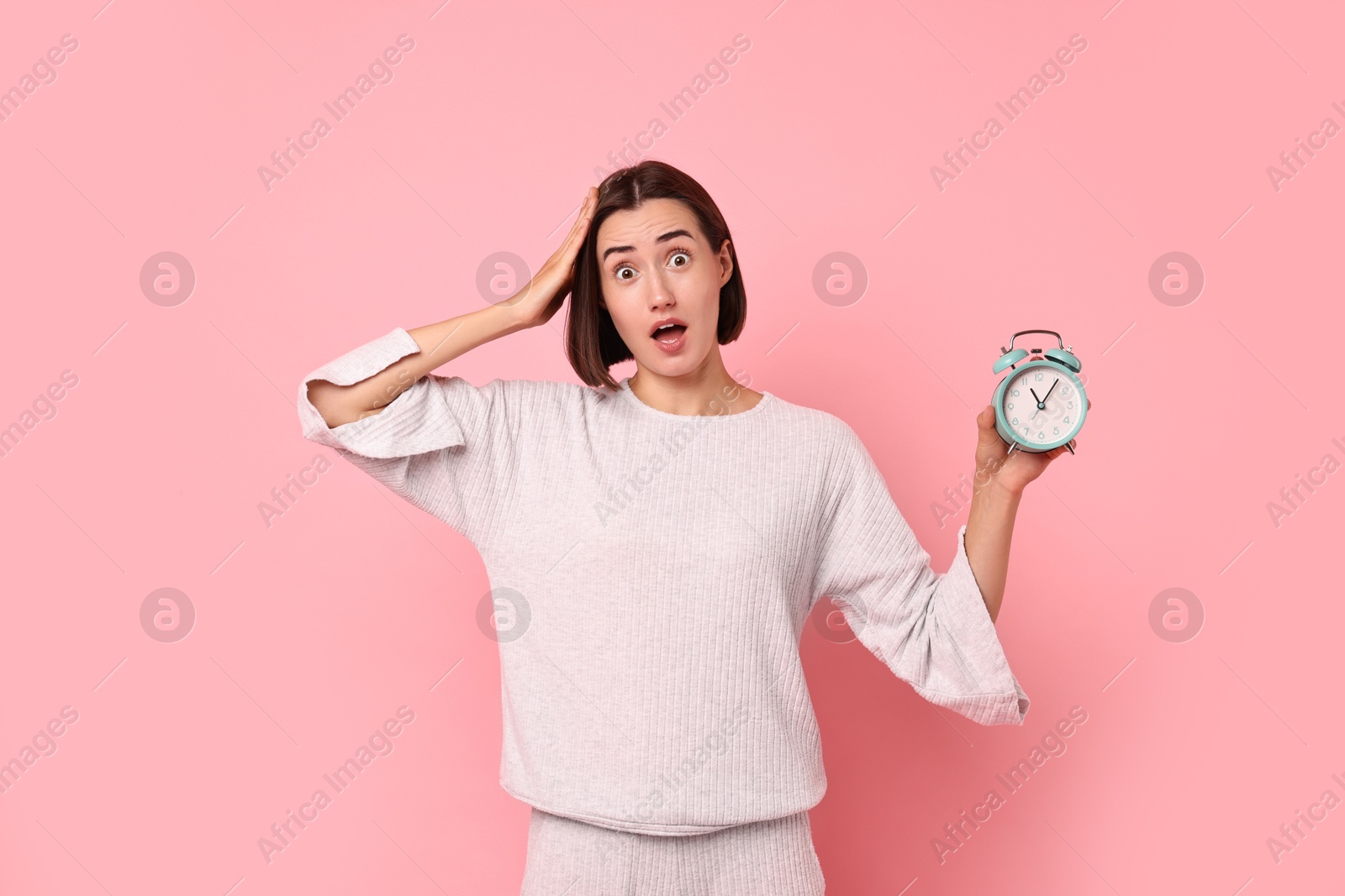 Photo of Overslept young woman with alarm clock on pink background