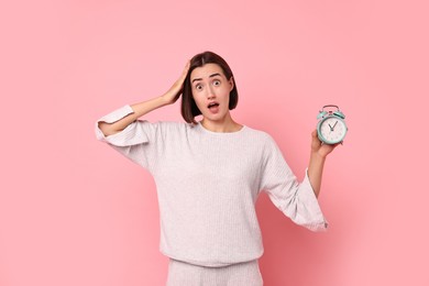 Overslept young woman with alarm clock on pink background