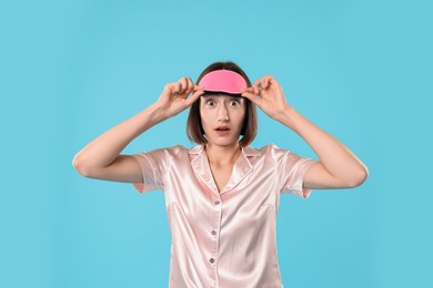 Overslept young woman with sleep mask on light blue background