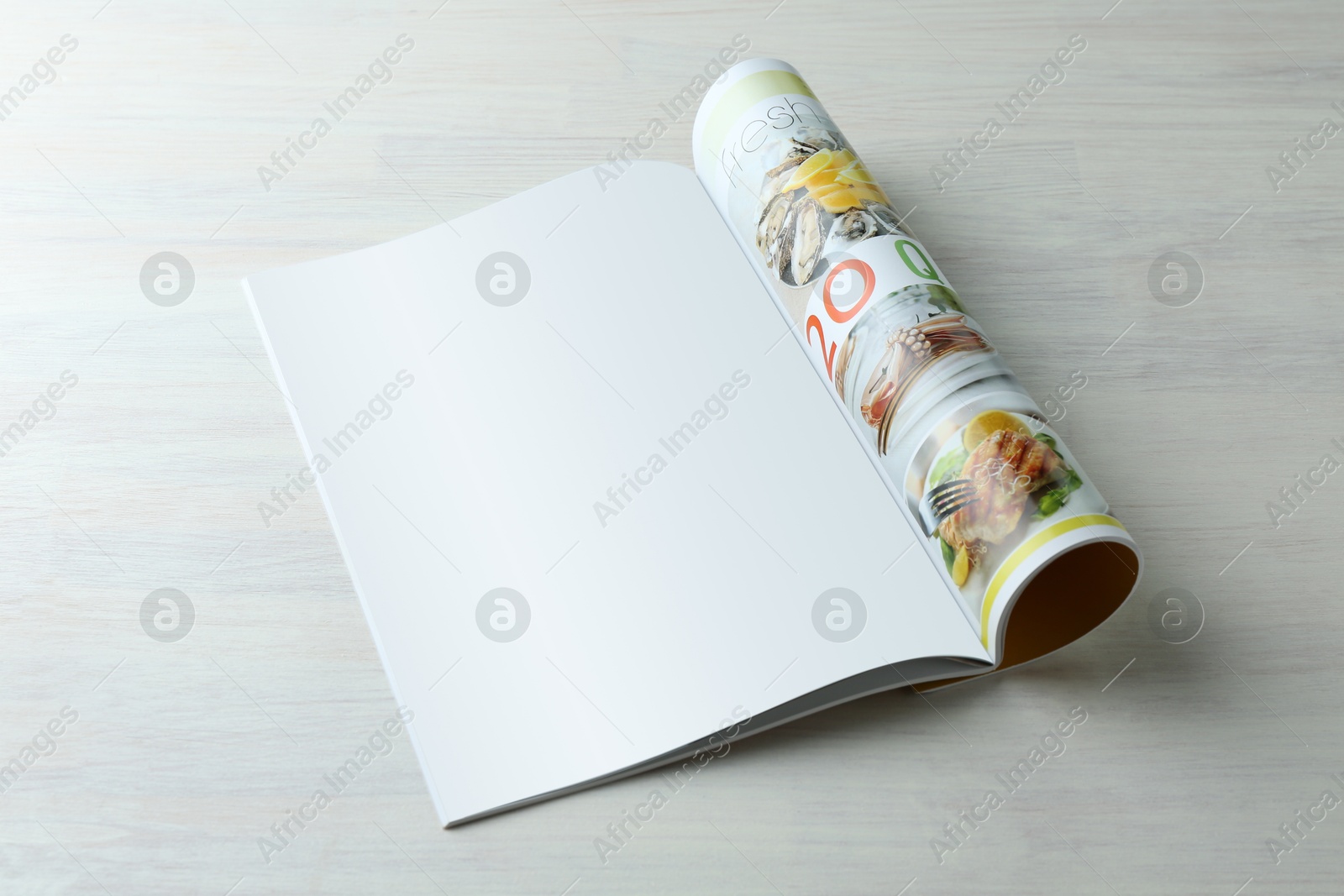 Photo of Open magazine on white wooden table. Mockup for design