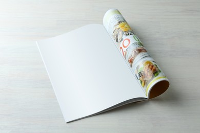 Open magazine on white wooden table. Mockup for design