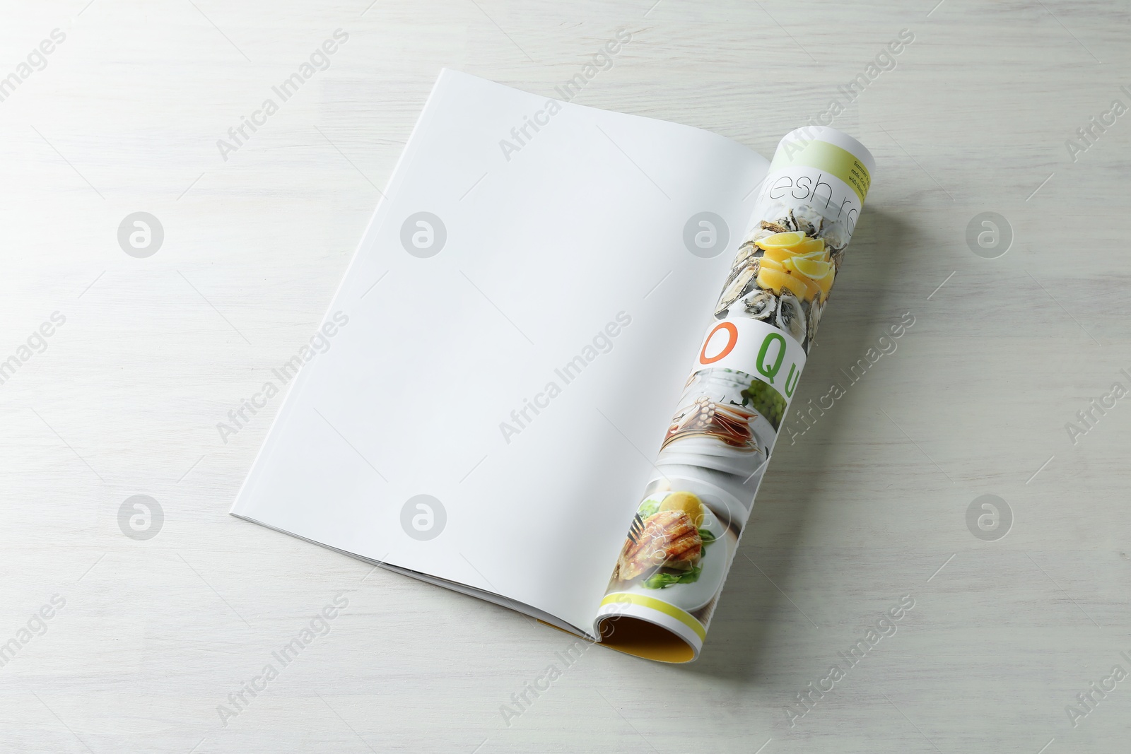 Photo of Open magazine on white wooden table. Mockup for design