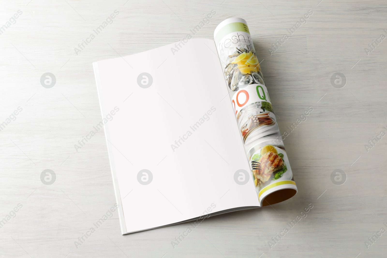 Photo of Open magazine on white wooden table. Mockup for design