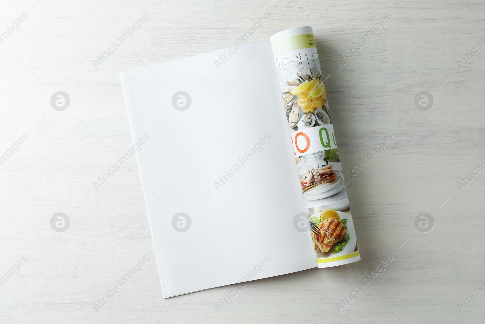 Photo of Open magazine on white wooden table, top view. Mockup for design