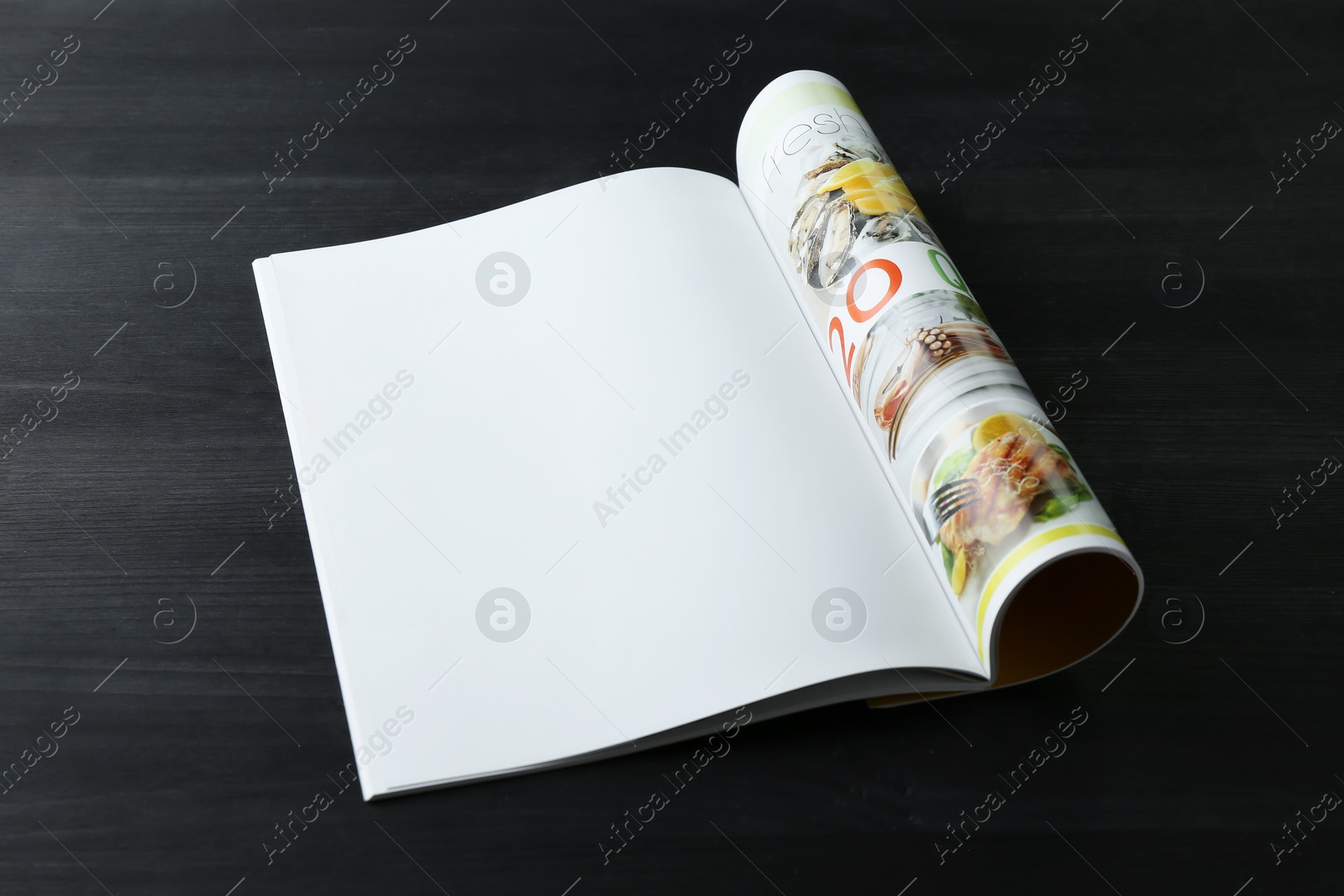 Photo of Open magazine on black wooden table. Mockup for design