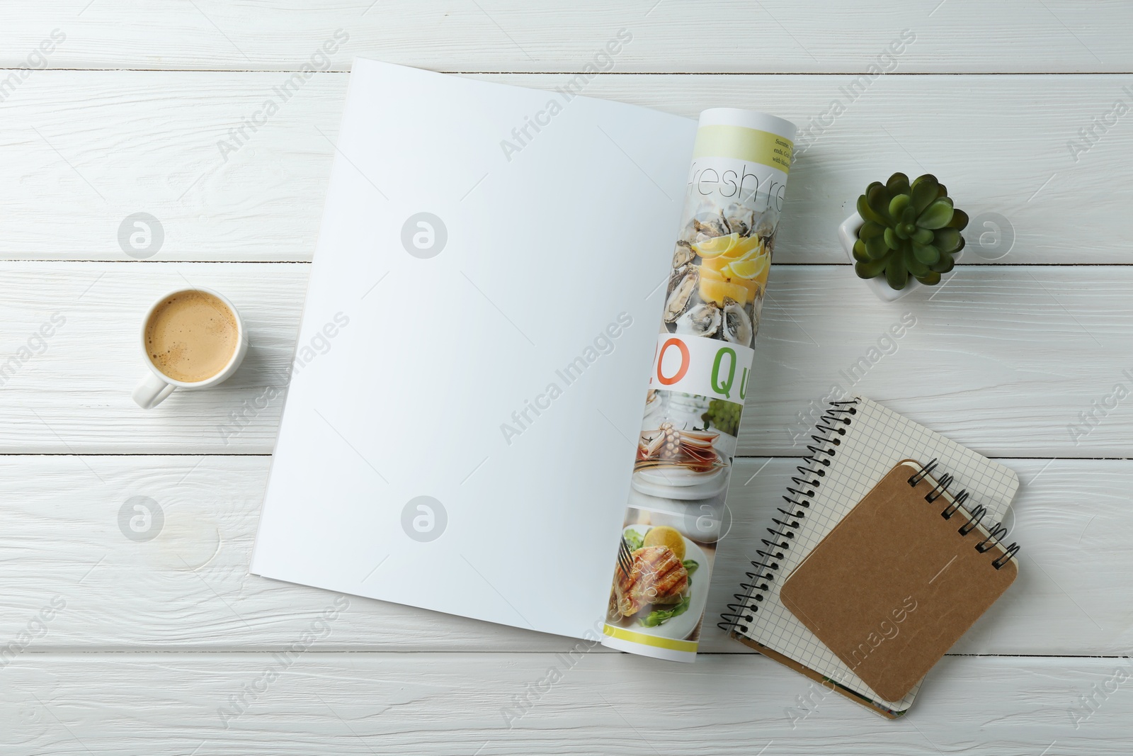 Photo of Open magazine with blank page, coffee, plant and notebooks on white wooden table, flat lay. Mockup for design