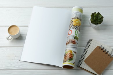 Open magazine with blank page, coffee, plant and notebooks on white wooden table, above view. Mockup for design