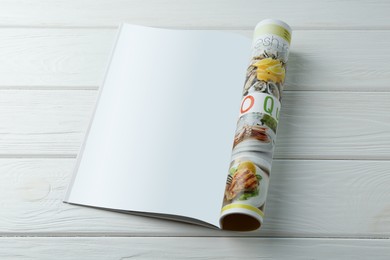 Photo of Open magazine with blank page on white wooden table. Mockup for design