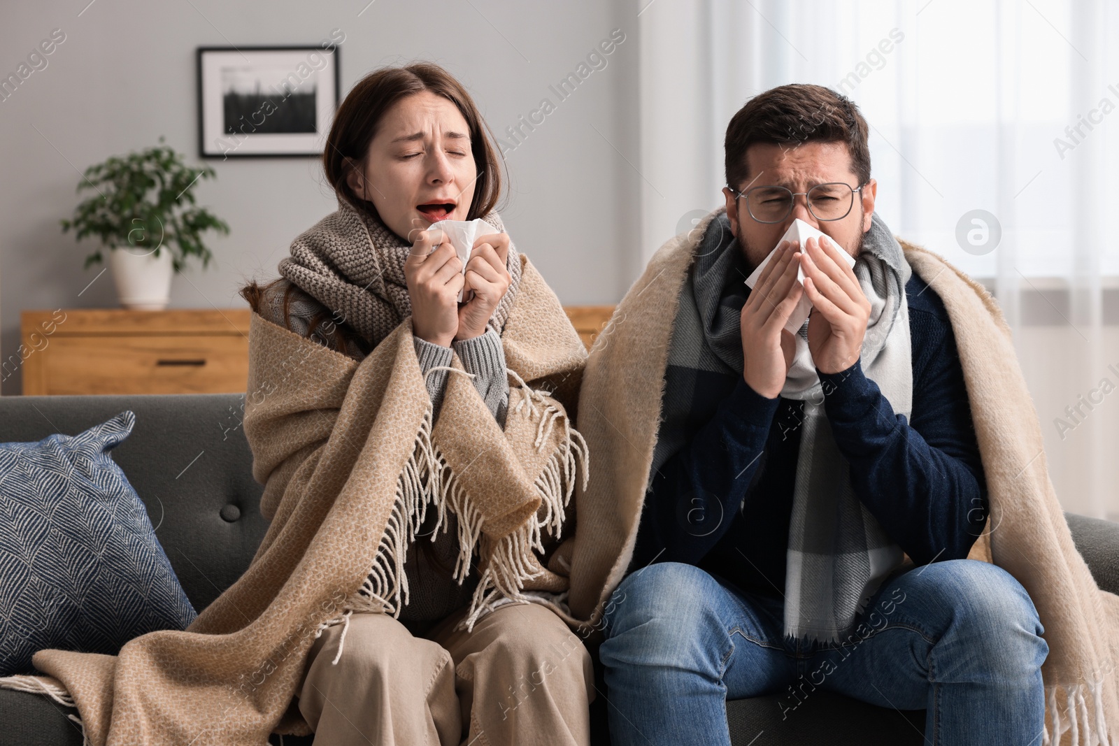 Photo of Cold symptom. Couple suffering from fever on sofa at home