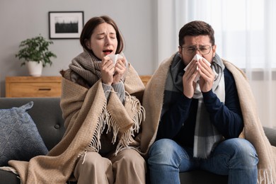 Photo of Cold symptom. Couple suffering from fever on sofa at home