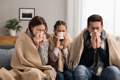 Cold symptom. Family suffering from fever on sofa at home