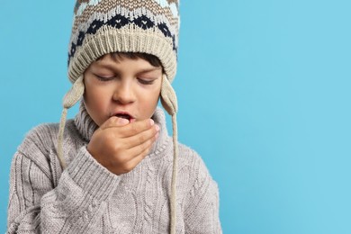 Cold symptom. Little boy suffering from fever on light blue background, space for text