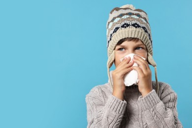 Photo of Cold symptom. Little boy with runny nose on light blue background, space for text