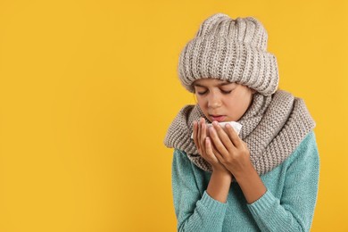 Photo of Cold symptom. Little girl with runny nose on orange background, space for text