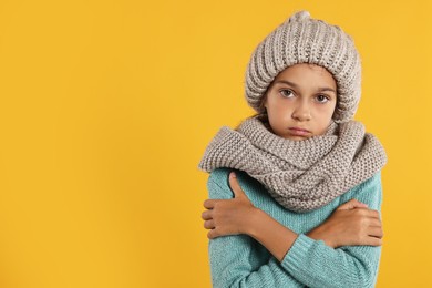 Photo of Cold symptom. Little girl suffering from fever on orange background, space for text